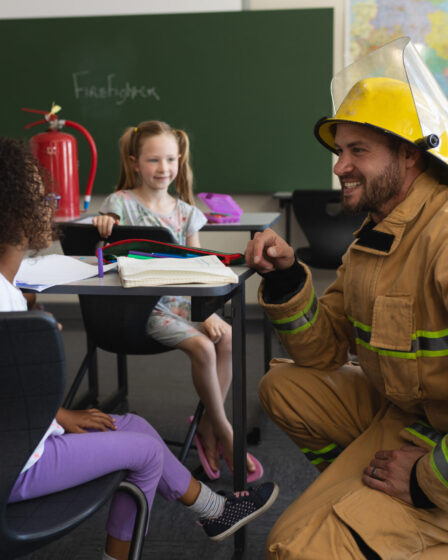 Firefighter teaching schoolgirls about safety and fire prevention.