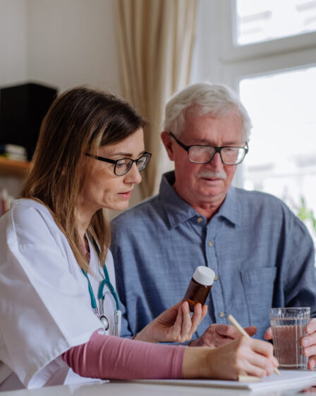 Healthcare worker assisting senior man with medication and healthcare services