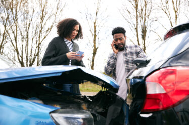 Couple exchanging car insurance details after a road incident.
