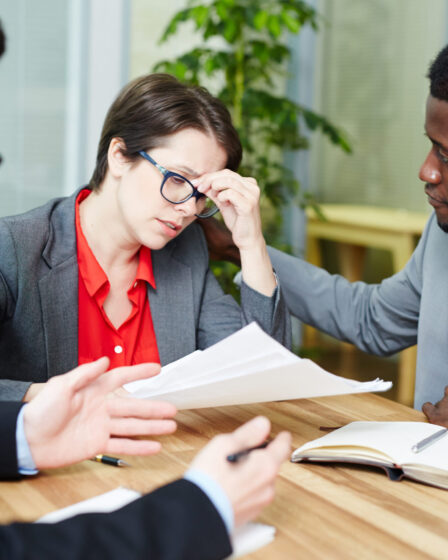 Stressed woman with glasses rubbing eyes over paperwork, illustrating personal injury and car accident aftermath.