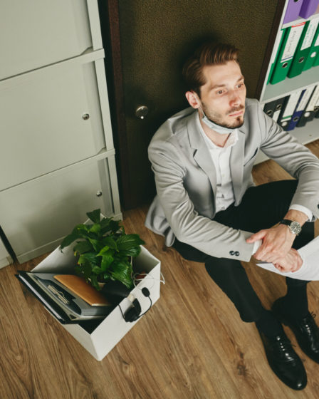 Stressed broker with papers and financial documents near safe, illustrating personal or professional crisis.