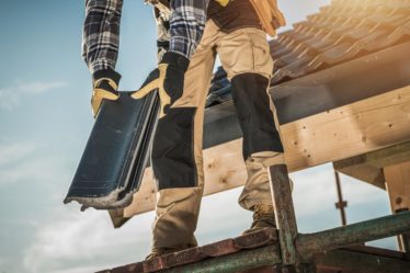 Construction Industry. Roofer with Ceramic Tiles in Hands. Roof Worker Closeup. House Rooftop Covering.