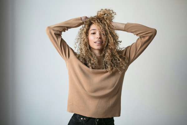 Woman with curly hair and healthy hair care, demonstrating hair styling and maintenance.