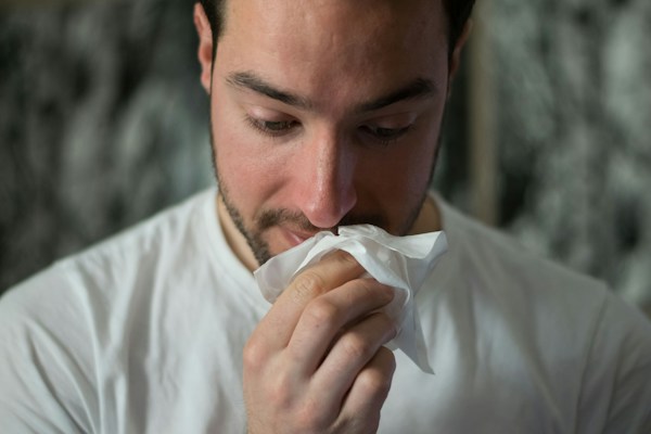 Man blowing nose into tissue, illustrating immune system support.