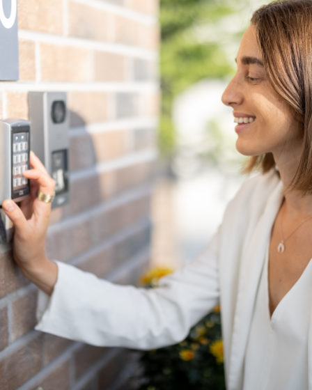 Woman entering code on keypad access control system for enhanced home security.