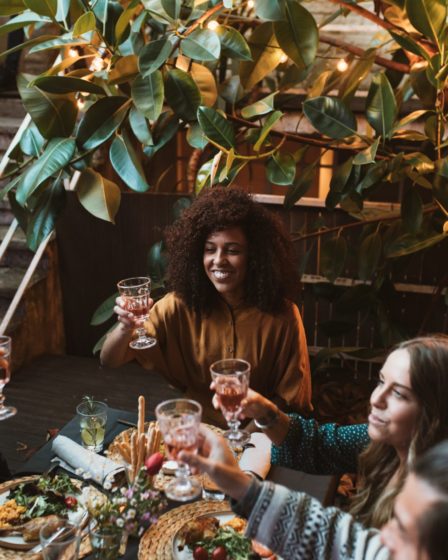 Woman smiling and toasting with a glass of rosé in a restaurant setting, celebrating new business opportunities and lifestyle.