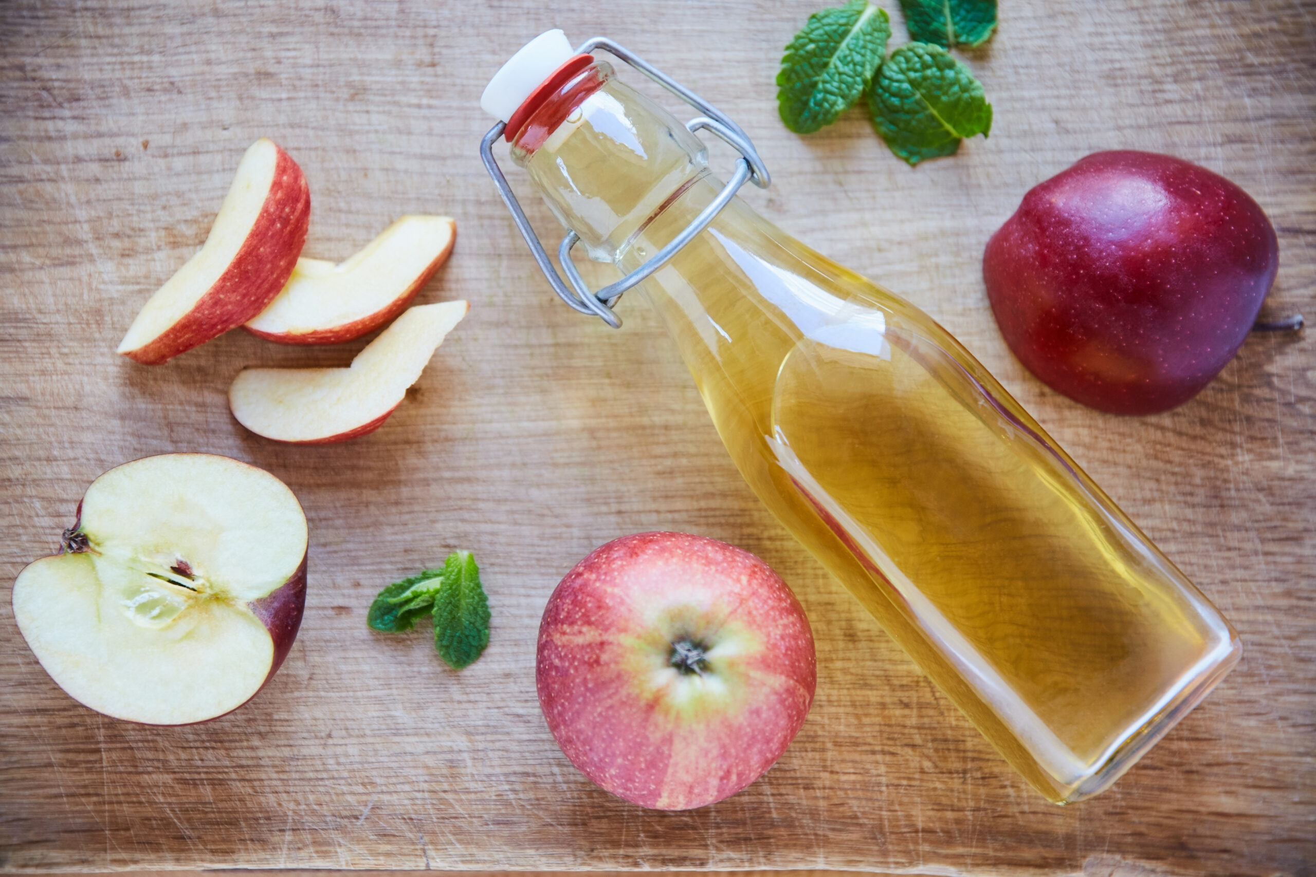 Bottle of apple cider vinegar and fresh apples with mint leaves