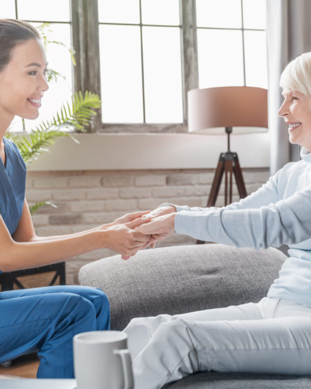 Female caregiver assisting senior woman at home, ensuring safety and well-being.