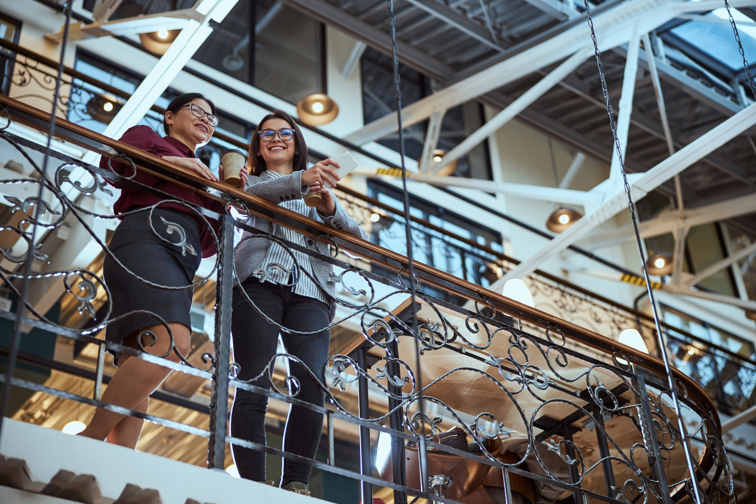 Two delighted women near cable railing system, discussing home safety and design.